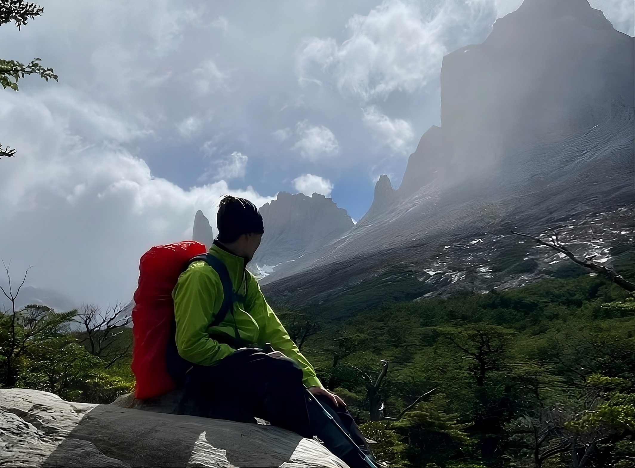 Lars Schlünzen sitzt auf einem Felsen und blickt in die Ferne. Im Hintergrund ist ein dichter Wald zu sehen.